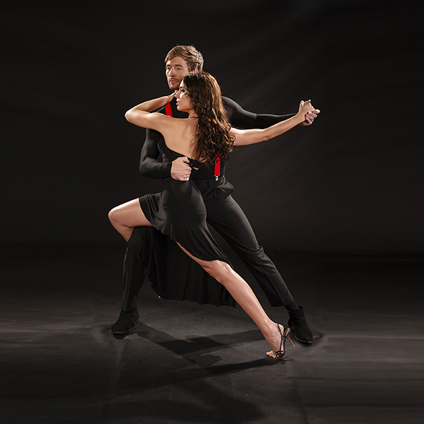Young beautiful couple dancing the sultry tango against black backdrop
